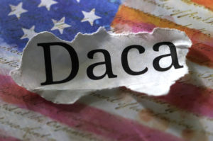 Paper with DACA written on it over American flag.